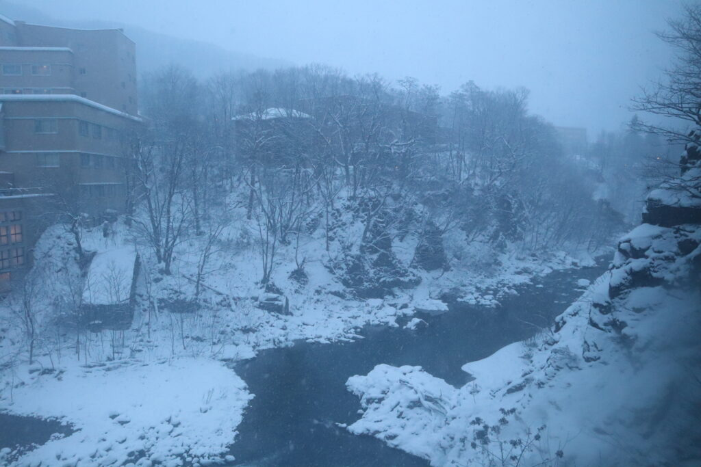 章月グランドホテル_ラウンジ_早朝の窓際から見える雪景色と渓流